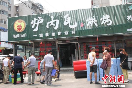 饮虎池街一烧烤店老板正在店铺门口甩卖桌、椅、纸巾等物品。　赵晓 摄